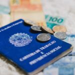 Carteira de Trabalho e Previdência Social com dinheiro e moedas brasileiras