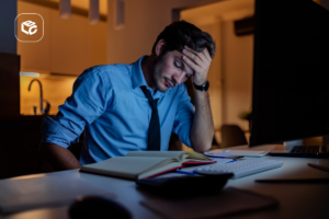 Homem de camisa azul estressado em frente a um computador à noite
